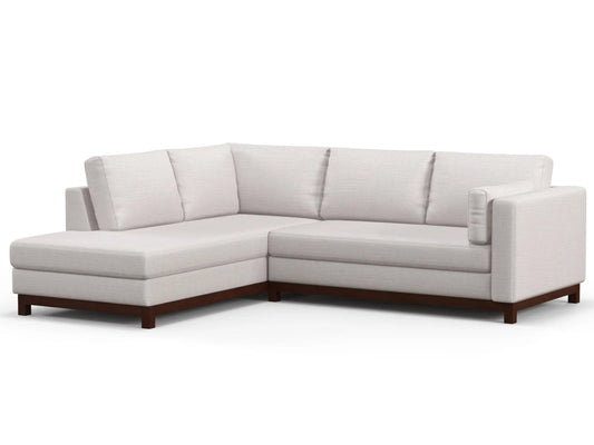 Introducing the Florida Bumper 96" Sectional: a contemporary L-shaped sofa featuring light beige upholstery and elegant dark wooden legs. This stylish piece includes three back cushions and an extended chaise lounge on the left, offering both sleek design and exceptional comfort.