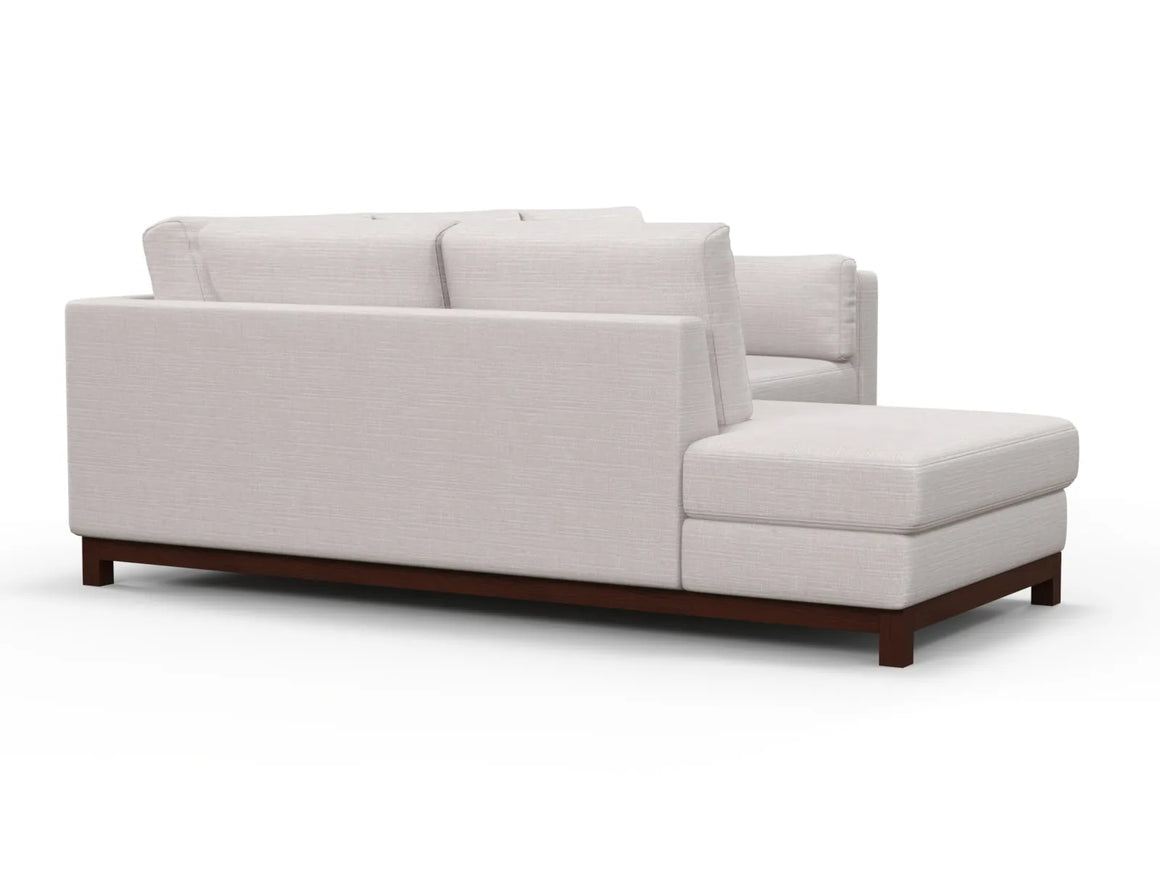 The Florida Bumper 96" Sectional is a beige L-shaped sofa featuring a cushioned back and seat on a wooden frame. Its minimalist design is highlighted against a white background.