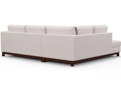 The Florida Bumper 96" Sectional is a beige, L-shaped sofa with clean lines and a modern design. It features plush cushions and a dark wooden base, positioned against a white background to highlight its minimalist style.