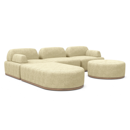 Introducing the Magna Preconfigured Sectional—a contemporary, beige-colored modular sofa with rounded edges, paired with a coordinating round ottoman. This sofa boasts plush cushions and a sleek texture, all displayed against a simple white background.