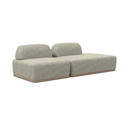 Introducing the Magna Preconfigured Sectional, a modern minimalist two-seater sofa adorned in textured light gray upholstery. It boasts a sleek, block design with low cushions and a wooden base, elegantly set against a plain white background.