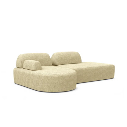 The Magna Preconfigured Sectional is a beige modern sofa with rounded edges, low backrests, and a chaise lounge on one side.