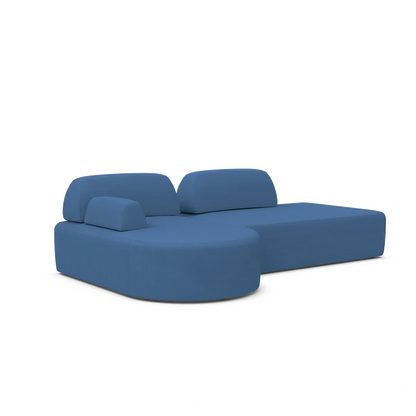 The Magna Preconfigured Sectional is a contemporary blue sectional sofa with a distinctive curved design, featuring multiple cushions and a chaise lounge extension on the right side. Its minimalist style stands out against a plain white background.