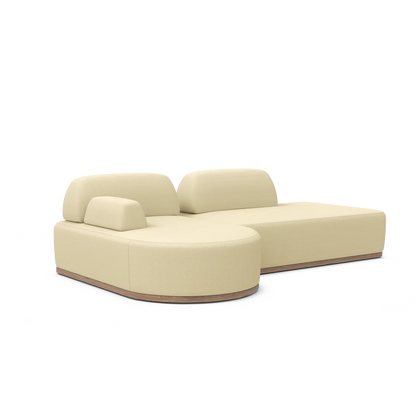 The Magna Preconfigured Sectional is a modern beige sofa with a low backrest and plush cushions, characterized by its smooth curves and minimalist design. It features a thin, flat base that enhances its contemporary and stylish appearance.