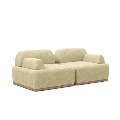 Introducing the Magna Preconfigured Sectional: a modern sectional in a sophisticated beige with a textured fabric finish. It boasts a low-profile design coupled with plush, rounded cushions and is supported by a minimalist wooden base. This sleek structure perfectly embodies contemporary style, making it an ideal choice for modern living spaces.