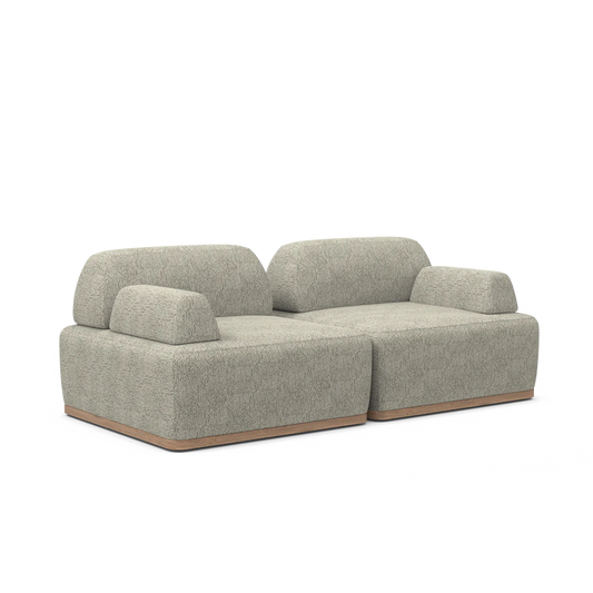 The Magna Preconfigured Sectional is a modern, beige sectional sofa with a textured fabric finish that features two thick cushioned seats and low backrests. It sits on a flat wooden base, offering a minimalist and contemporary design.