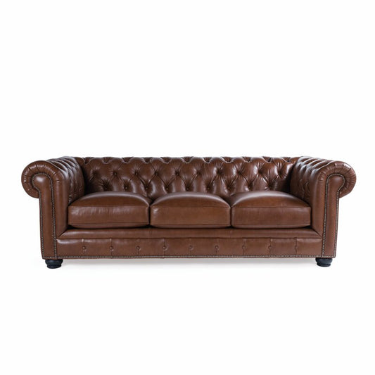 The Birch Lane Freddie 95'' Leather Sofa is a brown leather Chesterfield with deep button tufting, rolled arms, and a low backrest. Its classic design includes three seat cushions and nailhead trim along the edges.