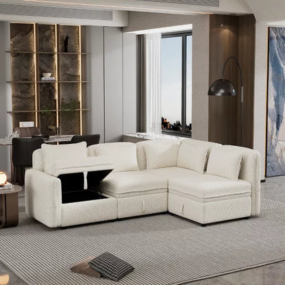 A modern living room featuring the 122.8" Minimalist Convertible Modular Sofa, an upholstered sectional from ModernLuxe in light beige, stylishly positioned on a textured rug. A side table hosts a small lamp, while the sofa's armrest includes an open storage compartment. The backdrop showcases a dining area and large windows offering a stunning city view.