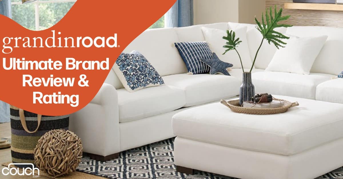 A cozy living room featuring a large white sectional sofa with various patterned throw pillows. A matching white ottoman sits in front of the sofa on a geometric-patterned rug. A tall vase with green foliage decorates the ottoman. Text over the image reads, "grandinroad. Ultimate Brand Review & Rating.