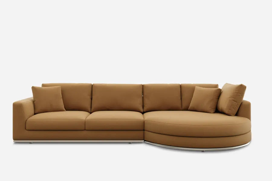 A modern, brown sectional sofa with a curved chaise on the right side. It features clean lines, three seat cushions, four back cushions, and minimalistic armrests, all in a soft fabric. The sofa rests on a low-profile base.