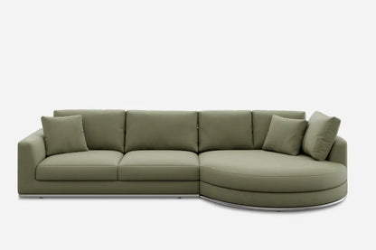 A green sectional sofa with three rectangular cushions on the left side and a stylish rounded chaise on the right, accompanied by several matching throw pillows, all set against a plain white background.