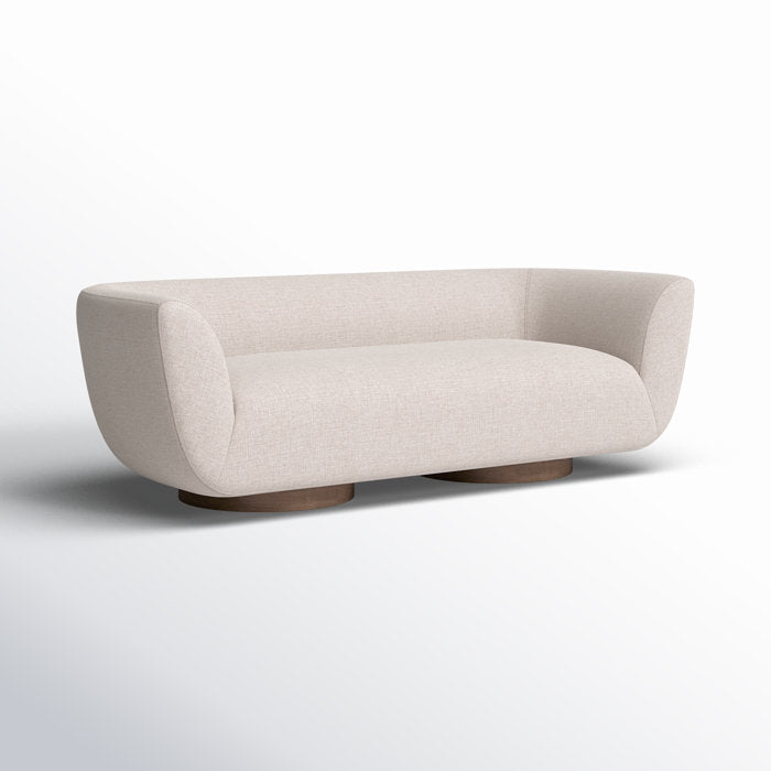 The Holloman 87'' Upholstered Sofa features a modern, minimalist design with a curved backrest and rounded wooden base against a white background, offering a sleek and contemporary look.