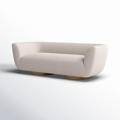 The Holloman 87'' Upholstered Sofa, featuring a modern design with off-white upholstery, curved edges, and low wooden legs, is showcased against a light gradient background.