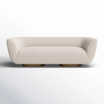 The Holloman 87'' Upholstered Sofa features a contemporary beige design with elegant curves and rests on two circular wooden bases, presented against a gradient light gray background.