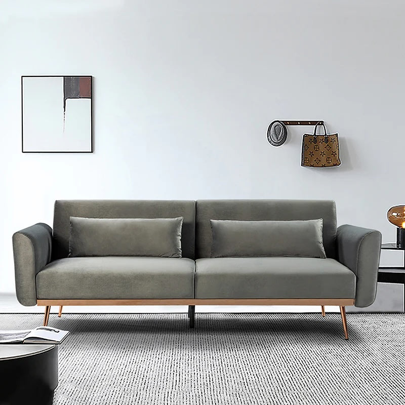 Modern living room with a gray sofa featuring two matching rectangular cushions, a minimalist abstract painting on the wall, a coat rack holding a hat and a handbag, and a small side table. The room has a neutral color palette with a gray rug on the floor.