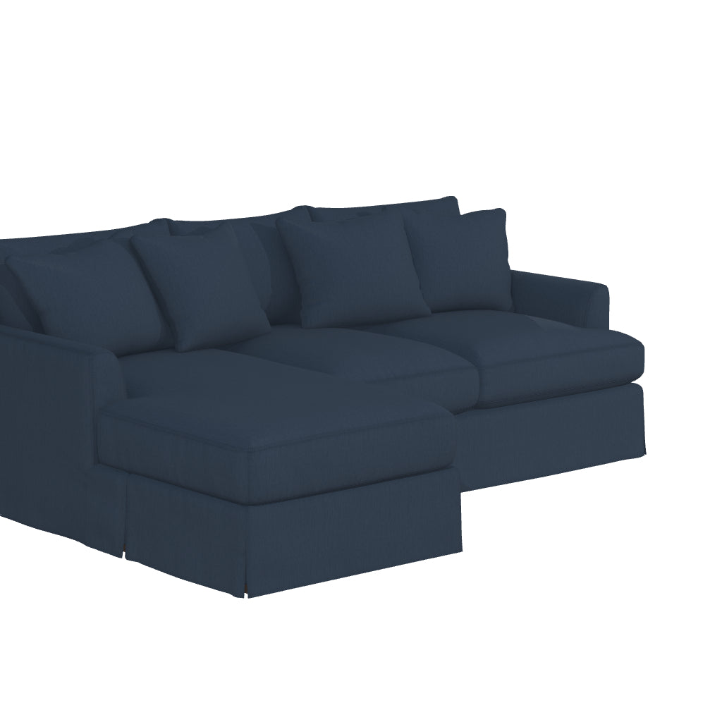 The Ava Chaise Slipcovered Sofa is a dark blue, L-shaped sectional with multiple cushions on both sections, boasting a clean, modern design. Its soft upholstery makes it perfect for a contemporary living room setting.