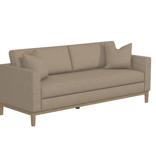 The Capri Sofa is a contemporary beige piece that boasts a boxy design with wooden legs, accompanied by two matching cushions.