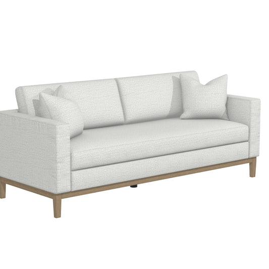 Introducing the Capri Sofa, a contemporary piece in white featuring a textured fabric finish. This sofa includes two seat cushions, two back cushions, and is complemented by two matching throw pillows. Its sophisticated design is enhanced by a wooden base and legs, offering a sleek and minimalist aesthetic.