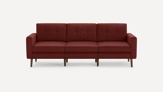 A Nomad Fabric Sofa in a three-seater design, featuring red upholstery with button-tufted back cushions and wooden legs, displayed against a plain white background.