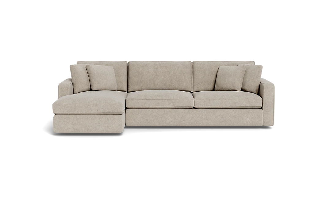 The James 3 Seat Left Chaise 92" Sectional in beige, set against a black background, features a chaise on the left side. It includes three seat cushions and four matching throw pillows, creating a modern and comfortable seating arrangement.