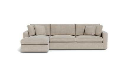 The James 3 Seat Left Chaise 92" Sectional in beige, set against a black background, features a chaise on the left side. It includes three seat cushions and four matching throw pillows, creating a modern and comfortable seating arrangement.