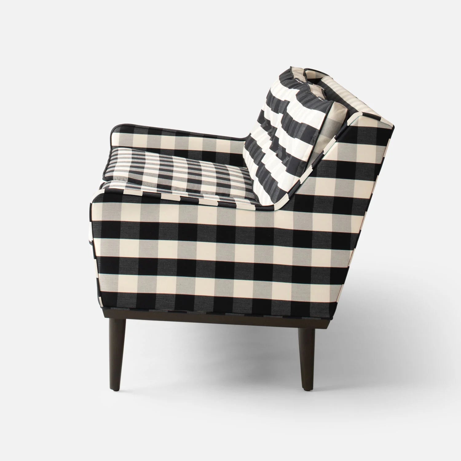 Side view of the Jack Sofa, featuring a modern black and white checkered pattern. The sofa boasts a square design with wooden legs, along with a cushioned seat and backrest, set against a plain white background.