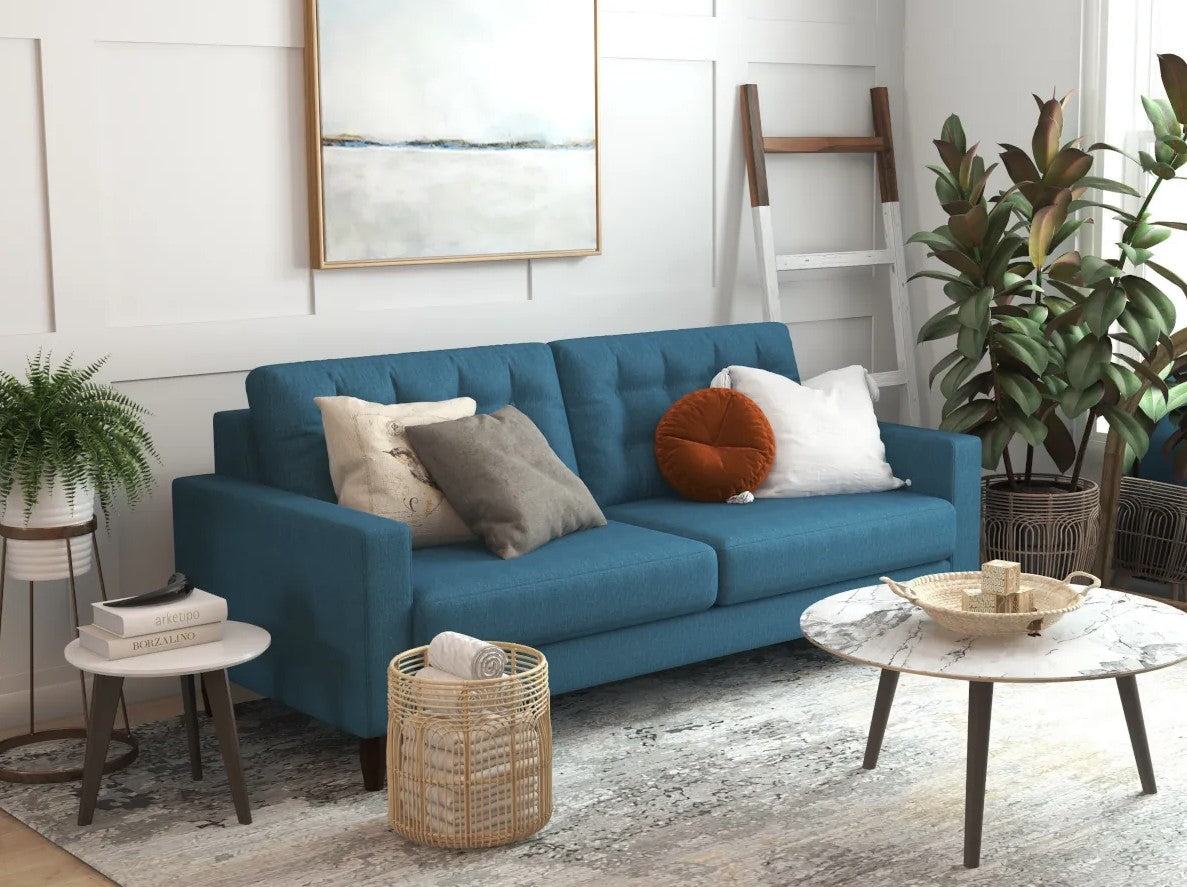 Blue sofa with four throw pillows in different colors. A painting hangs above the sofa and a coffee table is positioned in front. 