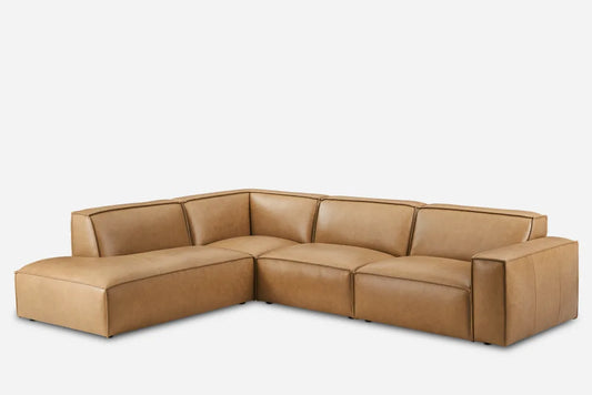 The Jonathan Leather Extended Side Chaise Sectional features a modern design with its brown leather upholstery. This sectional offers thick cushions and wide armrests, providing a spacious and comfortable seating area. With a plain white background, the sleek appearance of this sofa is prominently highlighted.