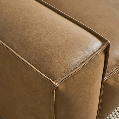 Close-up view of the corner of a Jonathan Leather Extended Side Chaise Sectional armrest, highlighting its smooth texture and stitching details, with the sofa resting on a light-colored carpet.