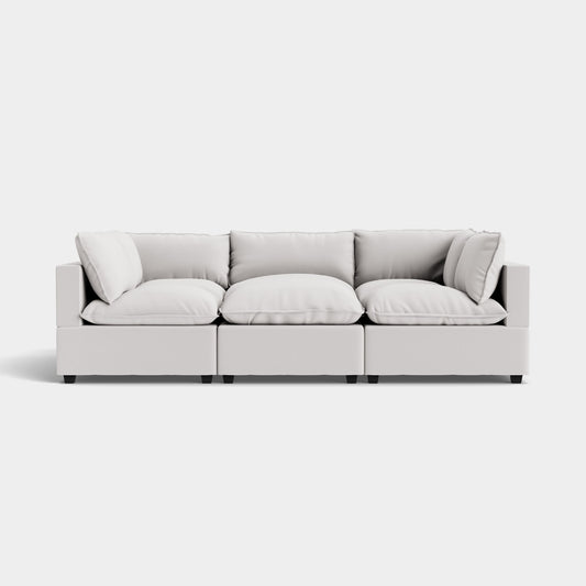 The Kova Pit is a modern sectional sofa with clean lines and light gray upholstery, featuring three seat cushions, soft plush back cushions, and block-style armrests. It creates a minimalist and contemporary look against a plain white background.