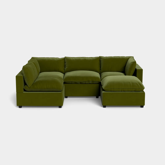 The Kova L Shape with Ottoman is a modular olive green sectional sofa featuring three corner pieces and two armless pieces, complete with plush, boxy cushions and low black legs, arranged elegantly in a U-shape on a plain white background.