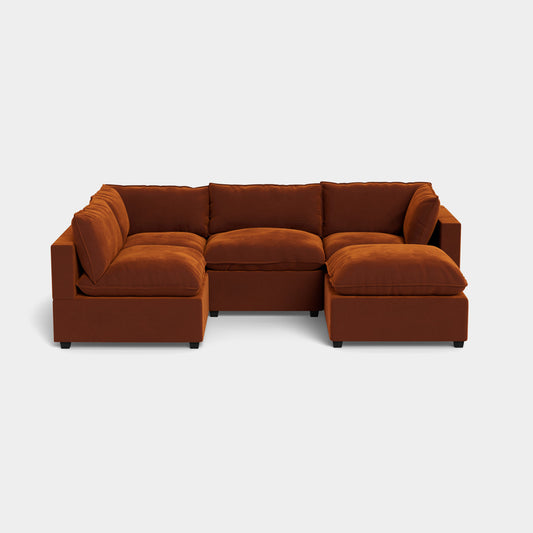 The Kova L Shape with Ottoman is a modular sectional sofa in rust color, featuring plush cushions and comprising five separate pieces arranged in an L-shape on a light gray background.