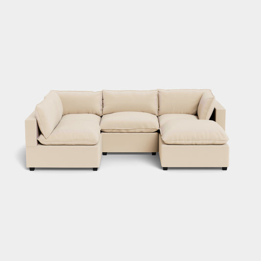 The Kova L Shape with Ottoman is a modern beige sectional sofa with cushions and low armrests, set on a plain light background.