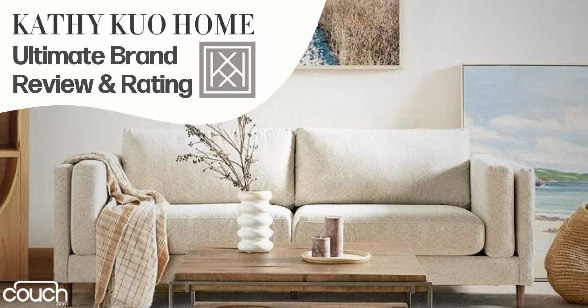 A cozy living room features a beige sofa topped with a plaid throw and decorative pillows. A white vase with branches sits on a minimalist coffee table. The background includes a large framed artwork of a beach scene and a textured wall hanging. Text: "KATHY KUO HOME Ultimate Brand Review & Rating.