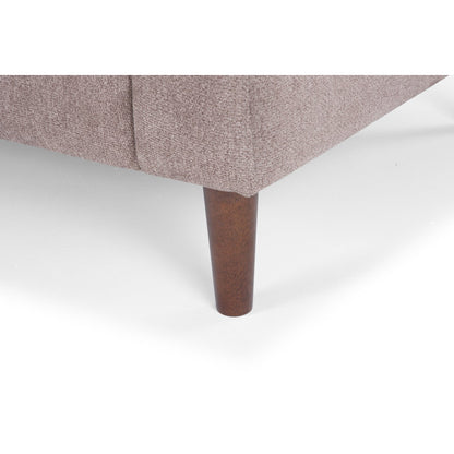 Close-up of the wooden leg of the Lana 85'' Upholstered Sofa, attached to its light brown upholstered surface, resting on a white background. The texture of the fabric is visible, and the wooden leg features a smooth, cylindrical shape.