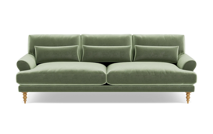 The Maxwell Custom Sofa is a chic piece, upholstered in luxurious green velvet, with three back cushions and two seat cushions. It is designed with rounded armrests and wooden legs, offering a modern and elegant appearance.