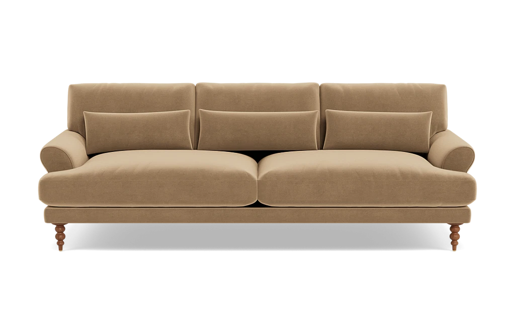 The Maxwell Custom Sofa is a beige, three-seater with plush cushions and rolled arms, supported by four wooden legs. It features three back cushions and a soft velvet-like texture, providing a cozy and elegant appearance against a plain background.