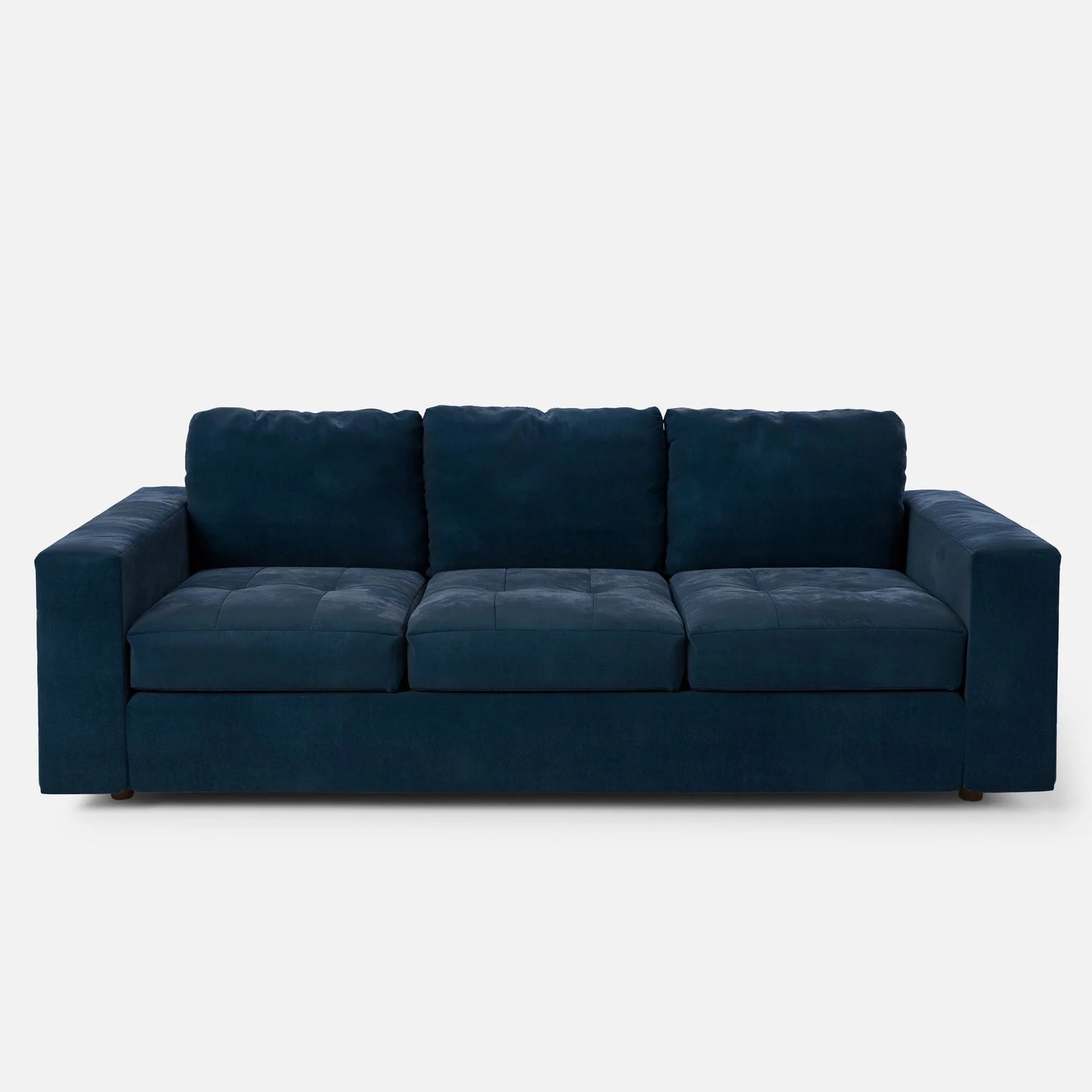 Marc Tufted Sofa: A contemporary, dark blue velvet sofa featuring three cushioned seats and broad armrests against a white background. This sofa boasts a plush, padded design with a minimalist aesthetic.