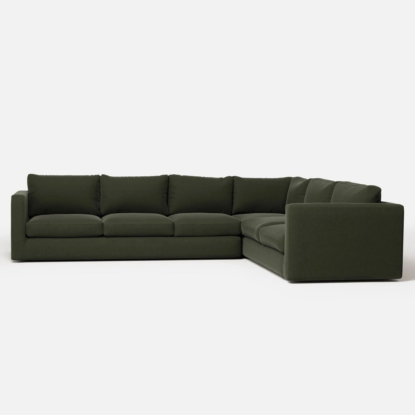 The Milo Sectional is a spacious L-shaped sofa in a luxurious dark green hue. It boasts thick, cushioned seating and backrests, offering both modern style and supreme comfort. The piece is showcased against a simple white backdrop.