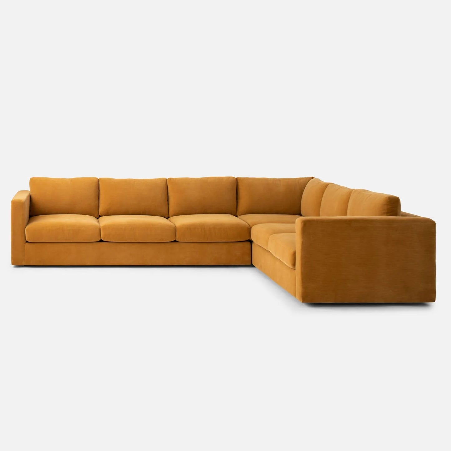 The Milo Sectional, a large L-shaped sofa upholstered in mustard yellow fabric, sits on a plain white background. It features plush cushions and boasts a modern, minimalist design.