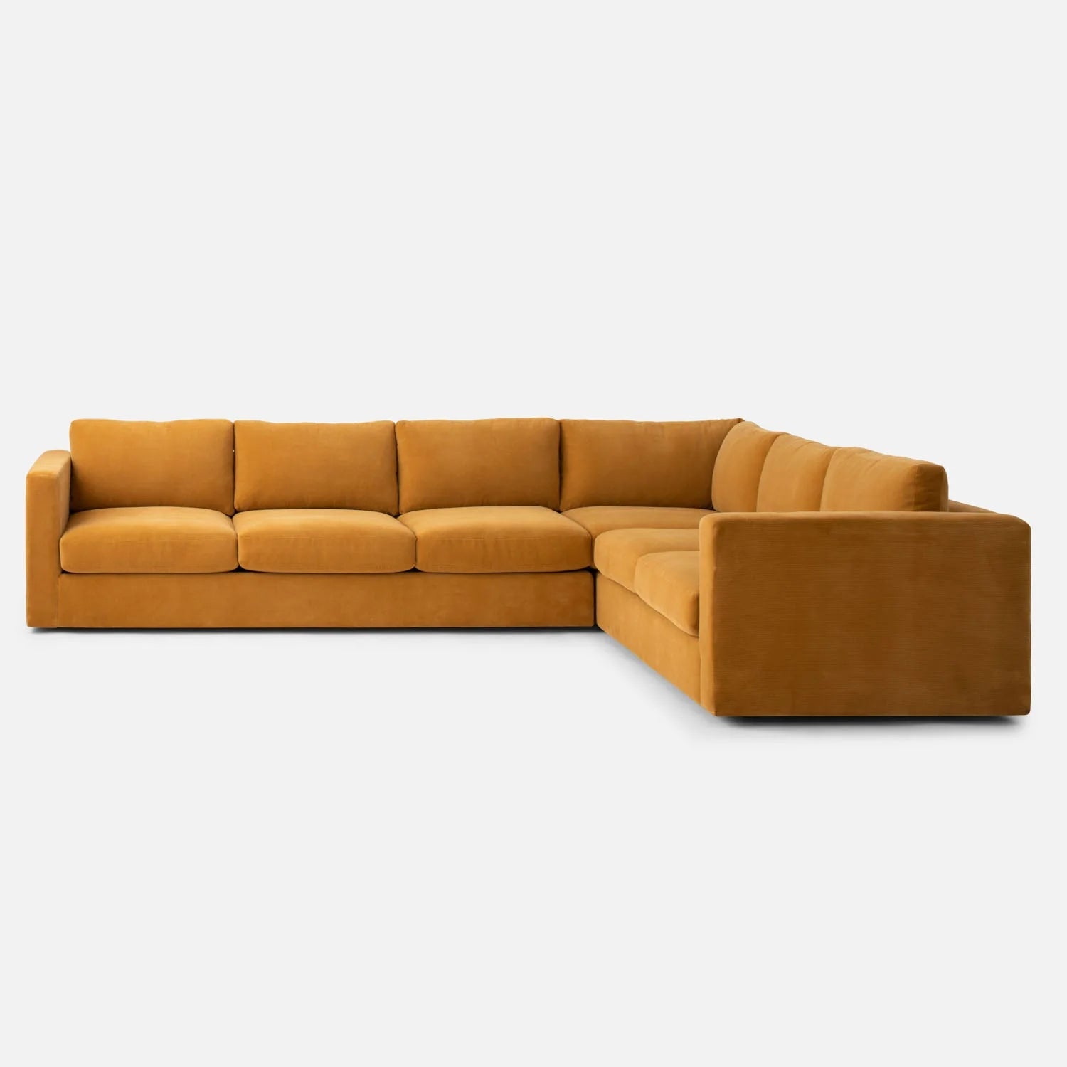 The Milo Sectional, a large L-shaped sofa upholstered in mustard yellow fabric, sits on a plain white background. It features plush cushions and boasts a modern, minimalist design.