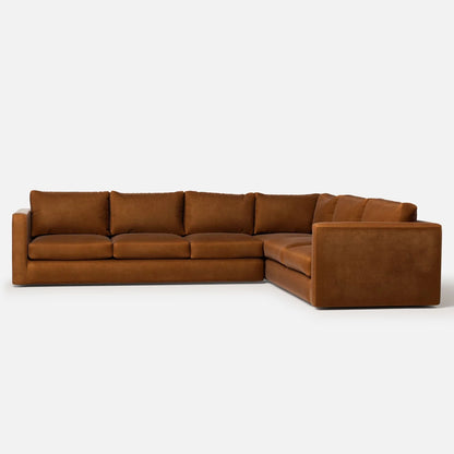 The Milo Sectional is a large L-shaped sofa in brown suede fabric set against a white background. It features deep cushions and a minimalist design.