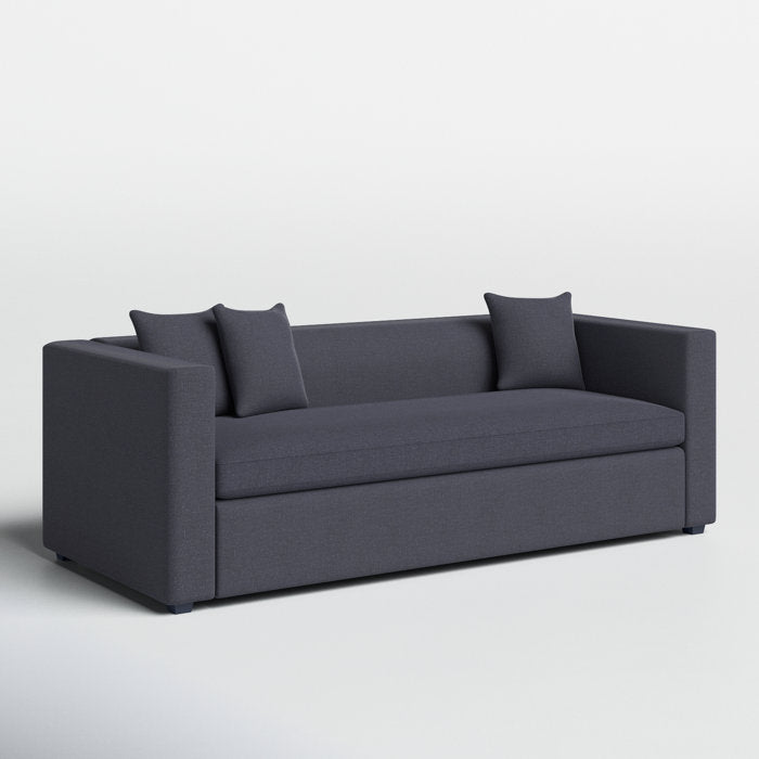 The Mono 81" Sleeper Sofa is a modern-style piece in dark gray, equipped with two square armrests and curved back edges. It includes two coordinating throw pillows and is positioned on a light gray floor against a plain white background.