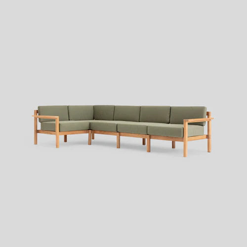 A modern L-shaped sectional sofa with green cushions and light wooden frame, set against a plain gray background.