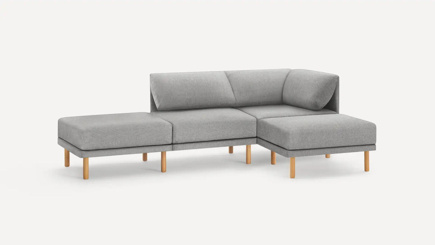 The Range Fabric 4-Piece Open Sectional Double Lounger Sofa is a modern gray L-shaped piece with wooden legs, consisting of three connected sections. It includes a chaise lounge on the left and features a cushioned backrest, all set against a plain white background.