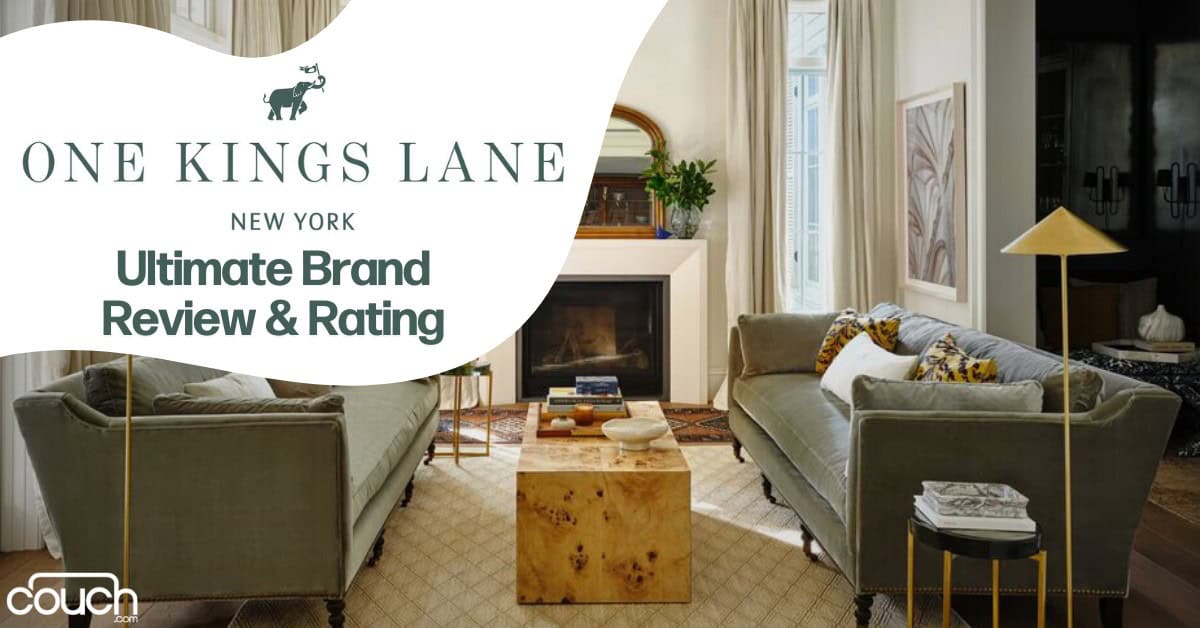 A stylish living room with two gray sofas facing each other. A wooden coffee table sits between them on a beige rug. Behind is a fireplace with a mirror and decor above. Text overlay reads: "One Kings Lane, New York, Ultimate Brand Review & Rating." Couch.com logo is at the bottom left.
