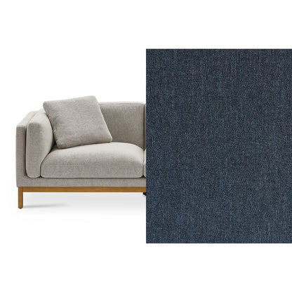 A contemporary Owen Chaise Sectional Sofa with a cushioned seat and back, featuring wooden legs in a modern grey upholstery. Adjacent to it is a large swatch of dark gray fabric, which may be an alternative upholstery option.