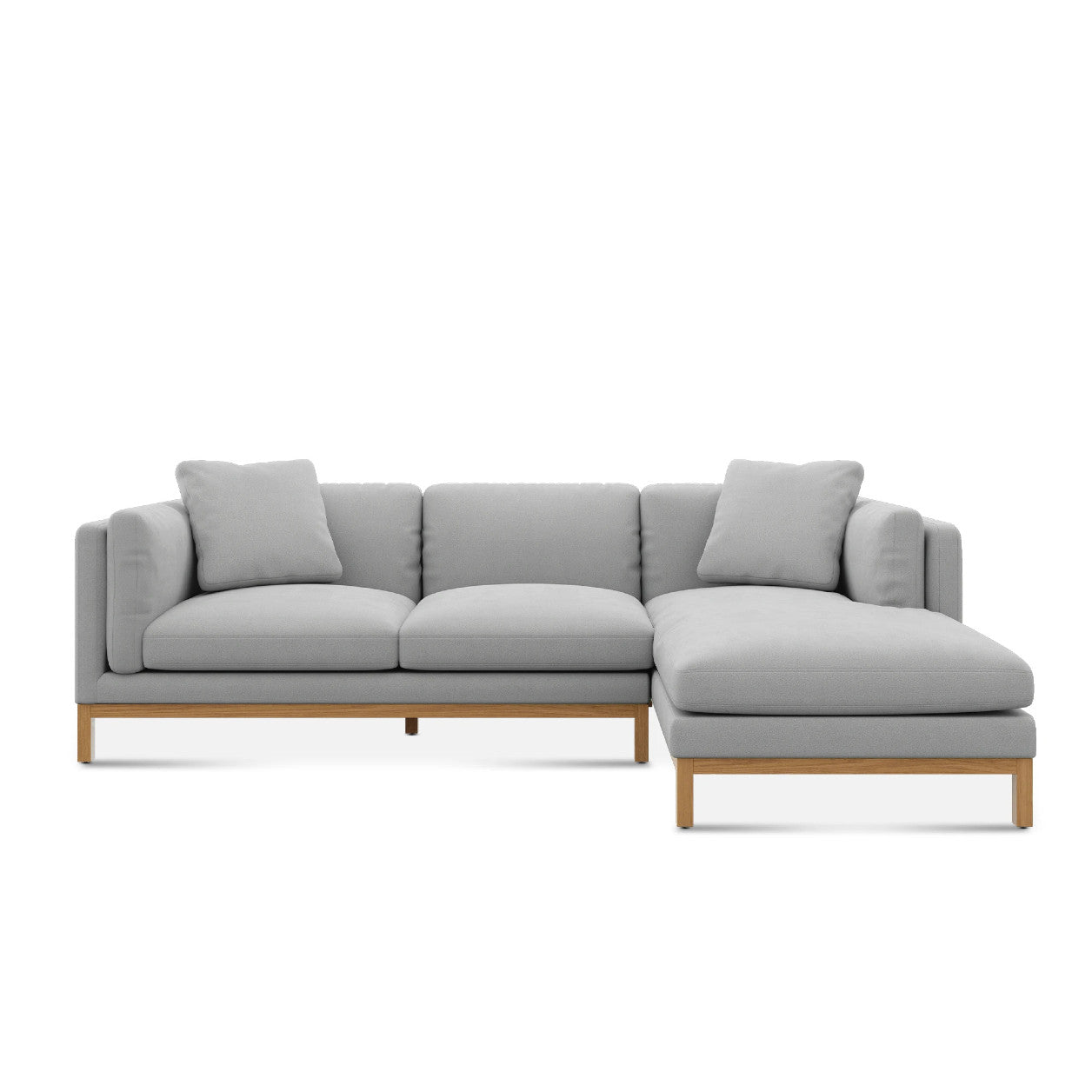 The Owen Chaise Sectional Sofa is a contemporary L-shaped design featuring light gray upholstery and wooden legs. It includes three seat cushions on the longer side along with an extended chaise on the right, complemented by matching back and side cushions.