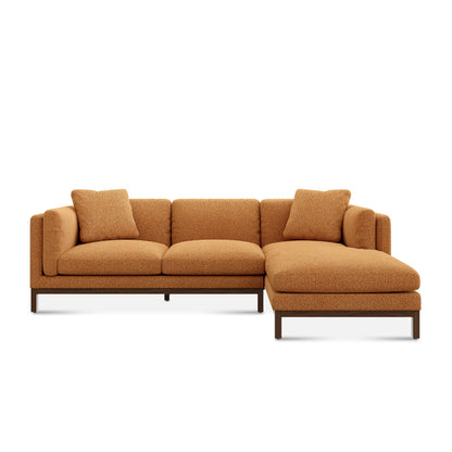 Introducing the Owen Chaise Sectional Sofa: a contemporary L-shaped sectional featuring orange textured fabric and coordinating throw pillows. Its design showcases clean lines, elevated on dark wooden legs.