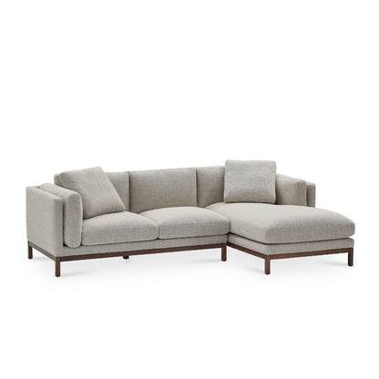 The Owen Chaise Sectional Sofa is a contemporary gray L-shaped design with a wooden frame, featuring a right-side chaise lounge and cushioned backrests. It includes two throw pillows positioned on the left side.